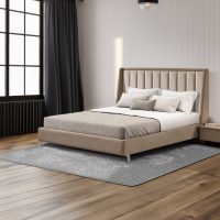 Cama de casal estofada em tom bege, com cabeceira alta e detalhes verticais acolchoados, inserida num quarto moderno e minimalista. O espaço conta com piso de madeira, tapete cinza, cortinas escuras e mesa de cabeceira, criando um ambiente sofisticado e acolhedor.