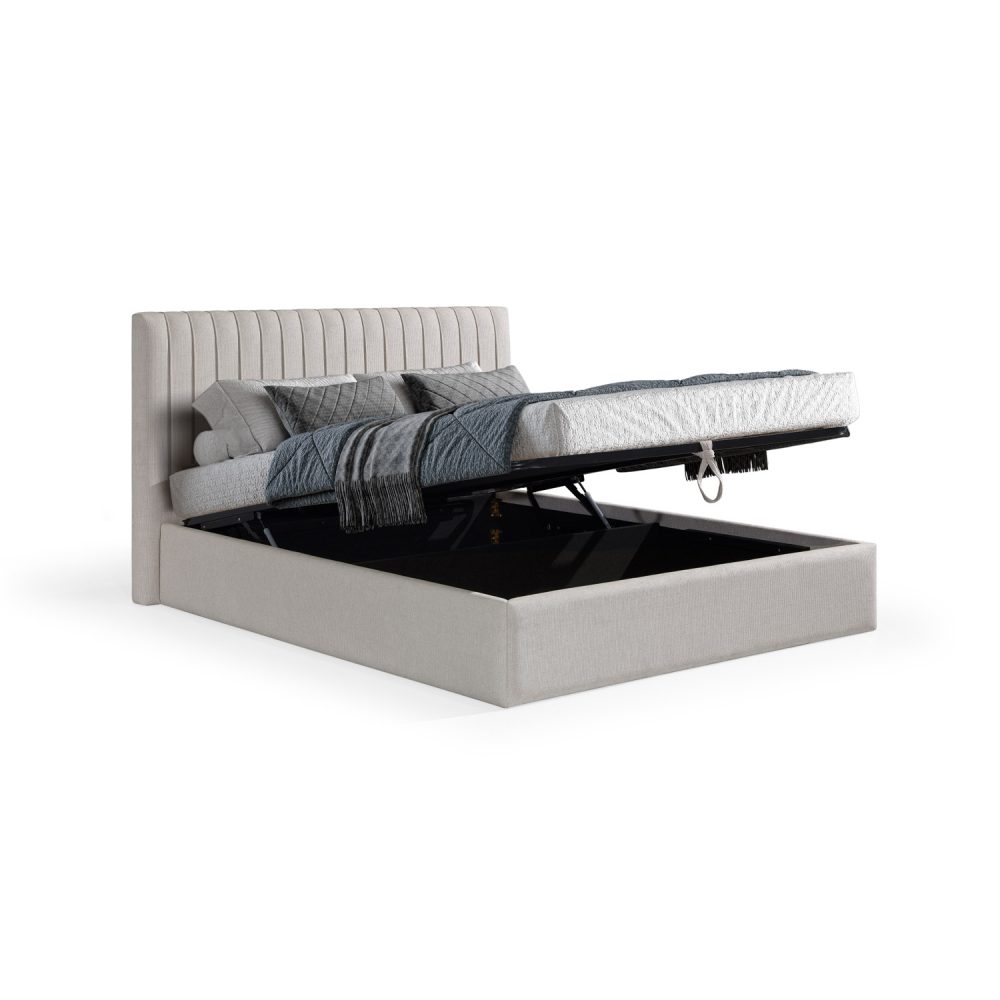 Cama moderna e estofada em branco, com uma cabeceira alta de costura vertical, decorada com roupa de cama cinzenta, incluindo edredão acolchoado, manta e almofadas, em tons elegantes e contemporâneos.