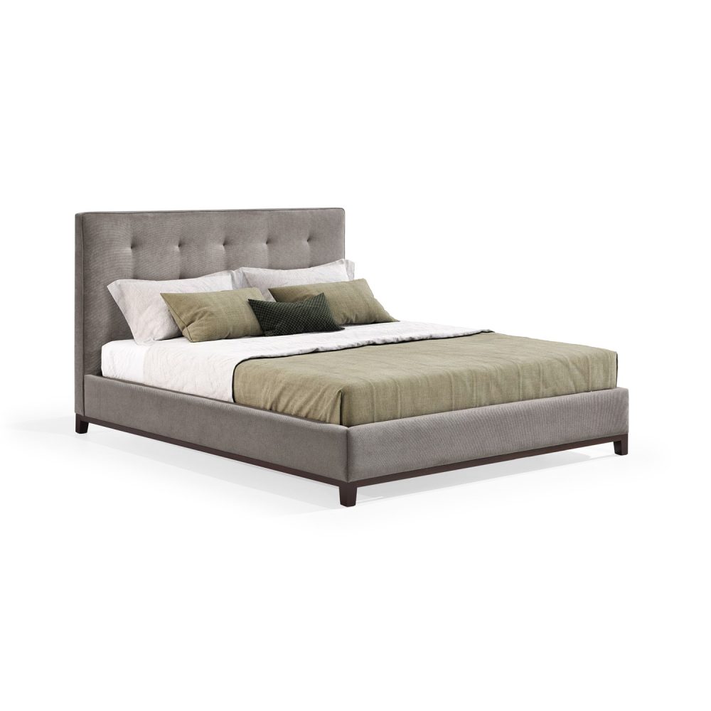 Cama moderna com cabeceira acolchoada e estofada em tecido bege, com lençóis brancos, uma manta verde e várias almofadas em tons de verde e branco. A estrutura da cama é revestida com tecido bege e possui pés de madeira escura.