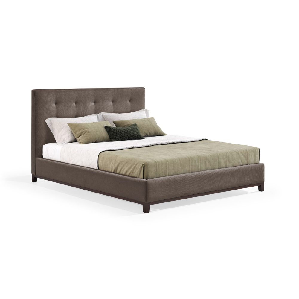 Cama moderna com cabeceira acolchoada e estofada em tecido castanho, com lençóis brancos, uma manta verde e várias almofadas em tons de verde e branco. A estrutura da cama é revestida com tecido castanho e possui pés de madeira escura.