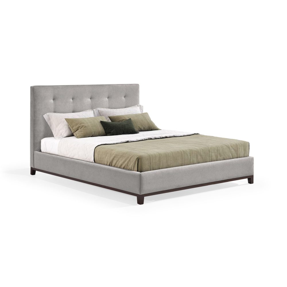Cama moderna com cabeceira acolchoada e estofada em tecido bege, com lençóis brancos, uma manta verde e várias almofadas em tons de verde e branco. A estrutura da cama é revestida com tecido bege e possui pés de madeira escura.