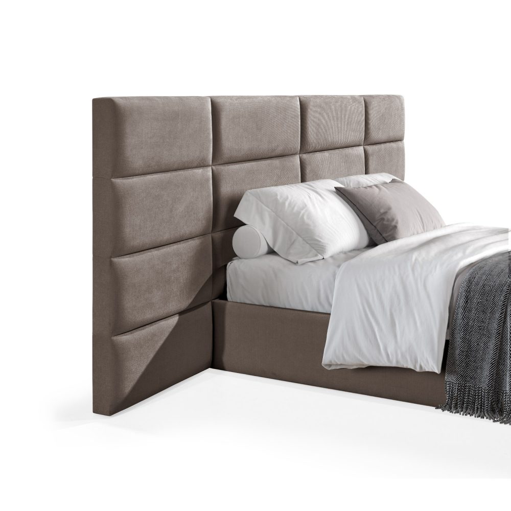Cama moderna com cabeceira acolchoada em castanho, lençóis brancos, cobertor cinzento e várias almofadas em tons de cinza e branco, com estrutura estofada no mesmo tecido cinzento.