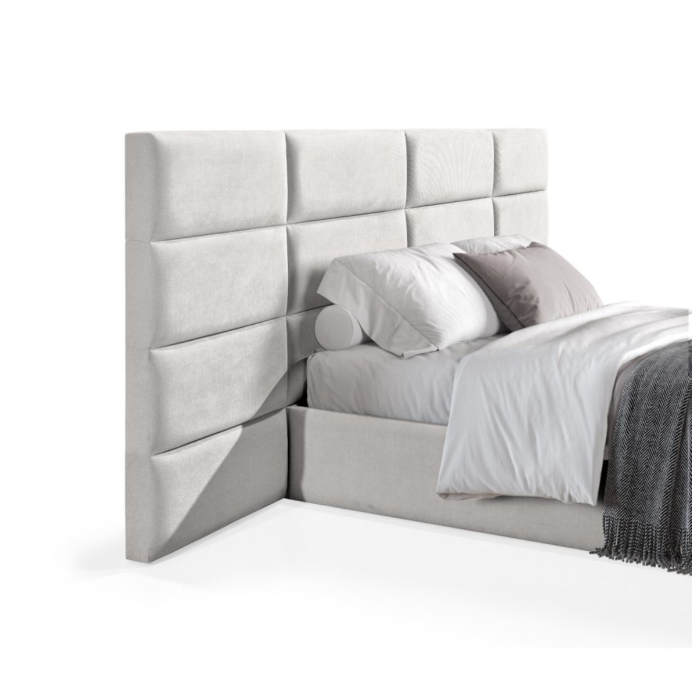 Cama moderna com cabeceira acolchoada em branco, lençóis brancos, cobertor cinzento e várias almofadas em tons de cinza e branco, com estrutura estofada no mesmo tecido cinzento.